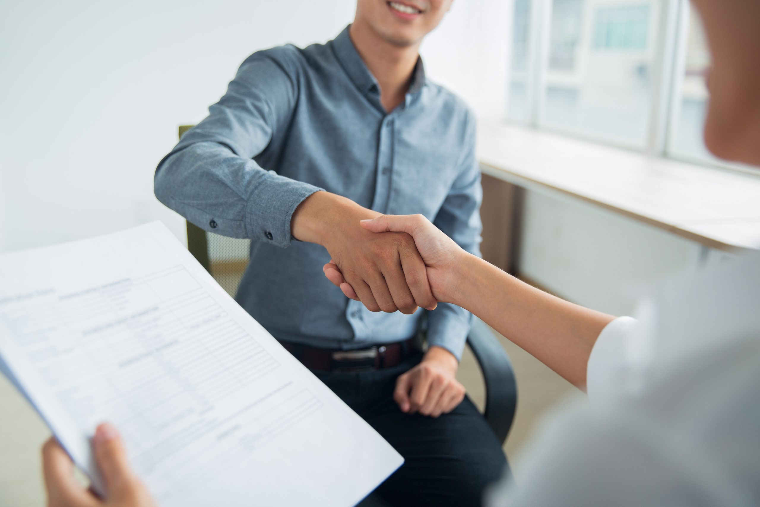 Smiling Asian Businessman Shaking Partners Hand Scaled